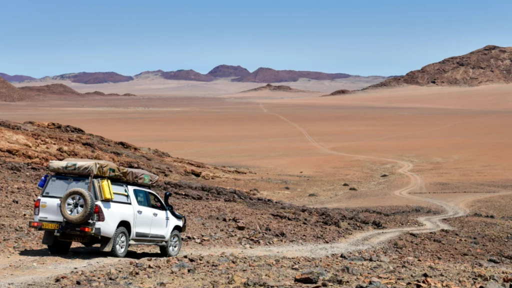 A Toyota Hilux double cab venturing through Namibia's breathtaking desert landscape, a perfect illustration of exploring Off the Beaten Path Destinations.