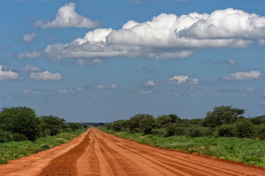 Leere Straße mit rotem Sand und Blick auf den Horizont