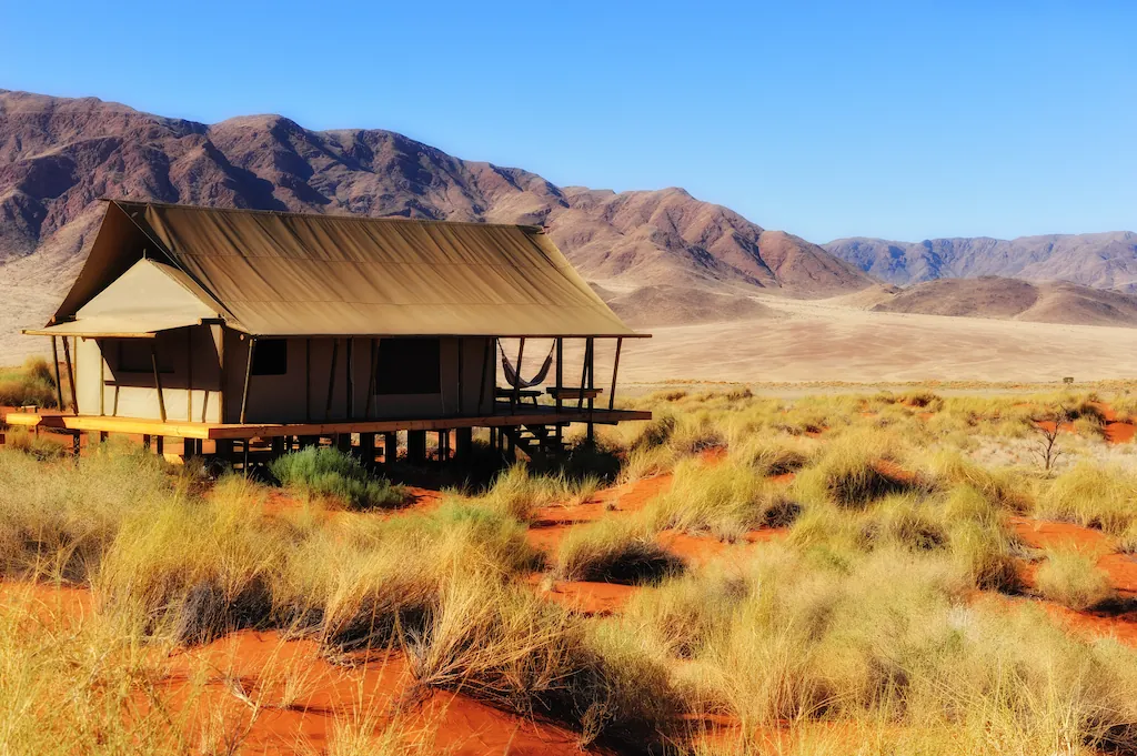 Safarizelt in der namibischen Wüste mit Bergkette im Hintergrund